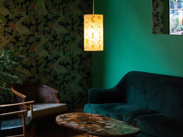 black and white floral padded armchair beside brown wooden round table